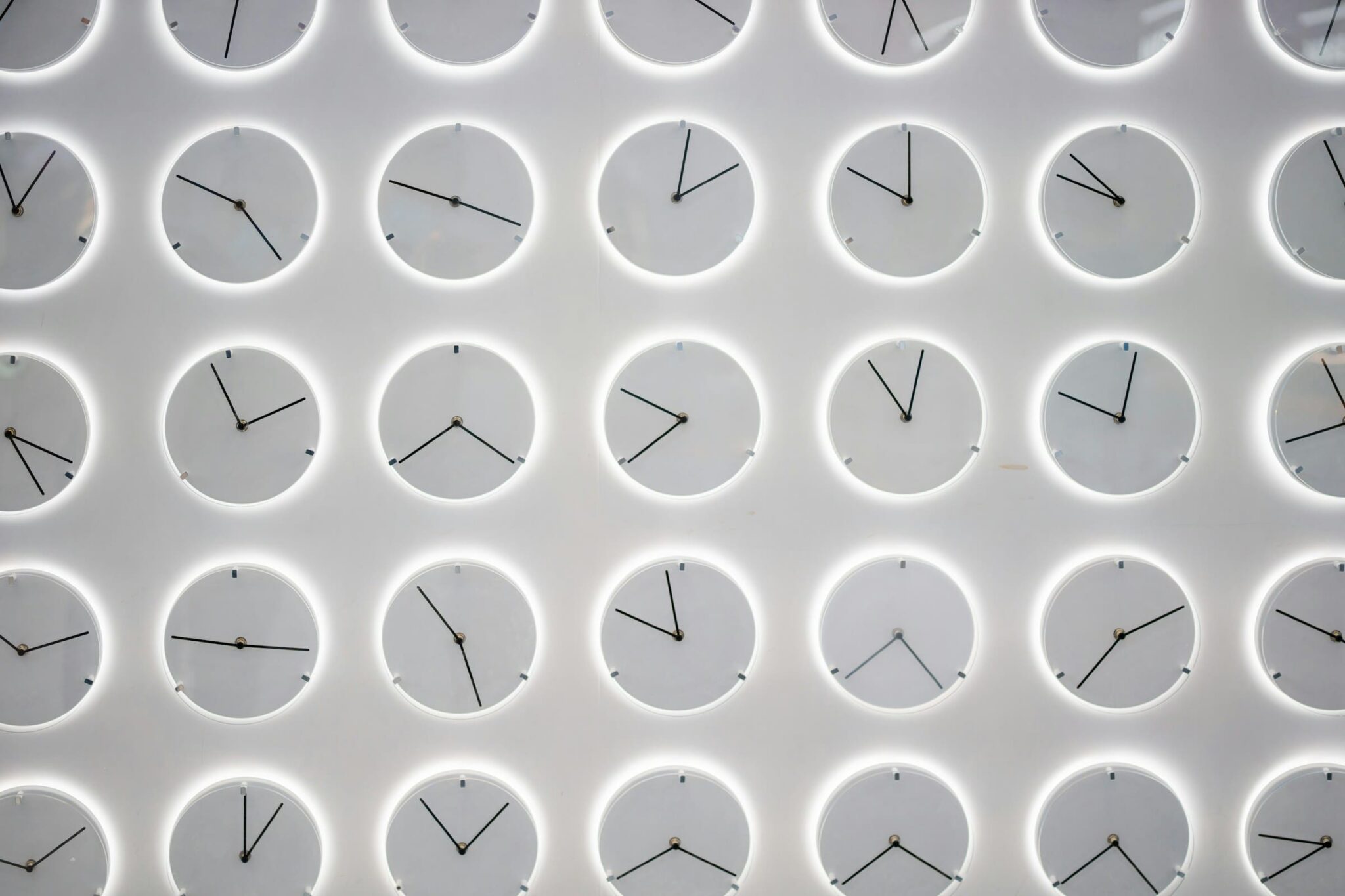 Multiple clocks displayed on a wall, symbolising delayed response to pressure and the growing risk of burnout over time.