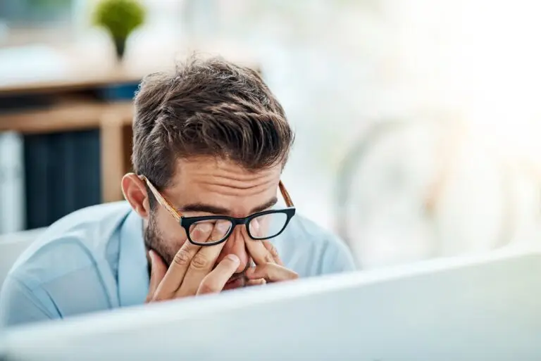 Business man showing signs of burnout with headache and stress while working at a computer in the office