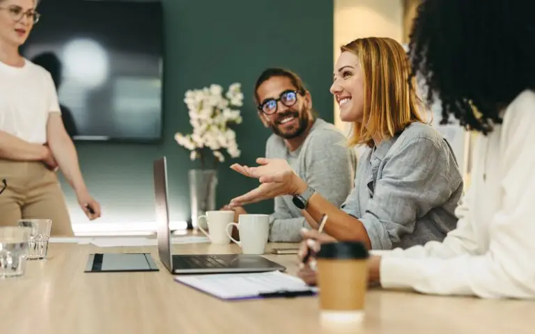 Cheerful businesswoman and colleagues demonstrating resilience during a hybrid team meeting in a modern boardroom.